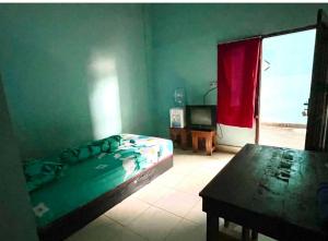 a bedroom with a bed and a table and a window at EXPRESS O 91669 Kost Amel Near Taman Mattirotasi in Parepare