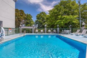 a swimming pool with chairs and a fence and trees at Sleep Inn Garner - Clayton in Edmondson