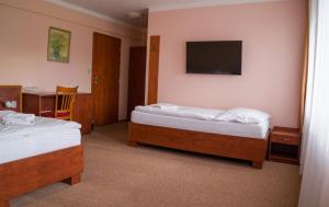 a hotel room with two beds and a television at Hotel Rudka in Kunštát