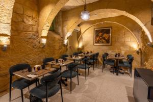 a restaurant with tables and chairs in a stone wall at The Vincent Boutique Hotel, BW Premier Collection in Valletta