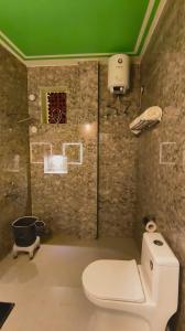 a bathroom with a white toilet and a green ceiling at The Stone Hamlet Retreat in Barkot