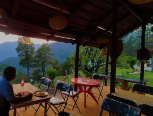 a man sitting at a table on a patio at The Stone Hamlet Retreat in Barkot