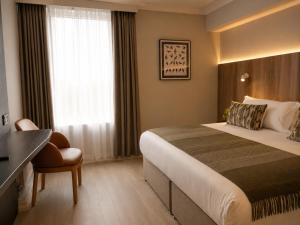 a hotel room with a bed and a desk at Springhill Hotel Kilkenny in Kilkenny