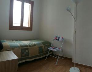 a bedroom with a bed and a chair and a window at Calle Santomera 17 in Torrevieja