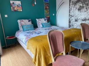 a bedroom with a bed with a yellow blanket and chairs at Suite Zen Grand Lit in Pierrelatte