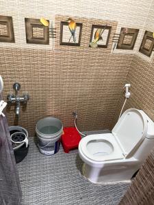 a bathroom with a toilet with paintings on the wall at A2KD Stay - Achyutam Keshavam Krishna Damodaram in Tiruvannāmalai +18 photos