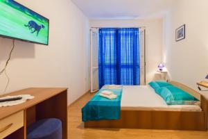 a bedroom with a bed and a desk and a tv at Apartments Slavica in Pomena