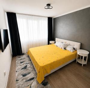 a bedroom with a bed with a yellow bedspread at NiC Apartment in Râmnicu Vâlcea