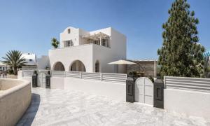 a white house with a palm tree in front of it at Terracotta Sunset Suites in Oia
