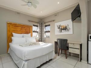 a bedroom with a bed and a desk and a chair at La Vue in Port Shepstone +20 photos