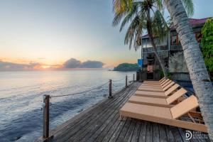 a dock with benches and a house on the water at Paradise Palm Beach Bungalows and Dive Center in Tulamben +77 photos