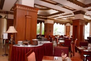 a dining room with tables and chairs in a restaurant at Quds Royal Hotel in Surabaya