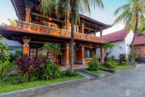 a house with a building with palm trees in front of it at Paradise Palm Beach Bungalows and Dive Center in Tulamben