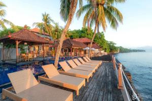 a row of chairs on a dock next to the water at Paradise Palm Beach Bungalows and Dive Center in Tulamben