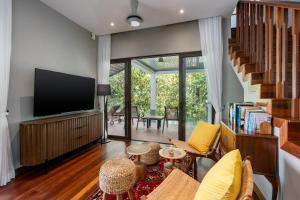 a living room with a flat screen tv and a couch at Ambong Pool Villas - Private Pool in Pantai Cenang