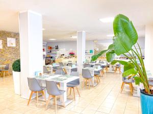 ein Restaurant mit Tischen und Stühlen und einer Pflanze in der Unterkunft Hotel Kinda in Castiglione della Pescaia