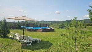 a couple of chairs and an umbrella next to a pool at Green Hills Villa in Sakhnovka