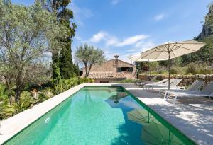 a swimming pool with an umbrella and chairs and a house at Finca Es Coste by Rentallorca in Pollença