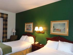 a hotel room with two beds and a green wall at Ruskin Inn Tampa-Sun City Center in Ruskin