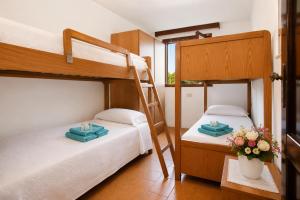 two bunk beds in a room with flowers on a table at Baja Sardinia Sea View And Pool B in Baja Sardinia