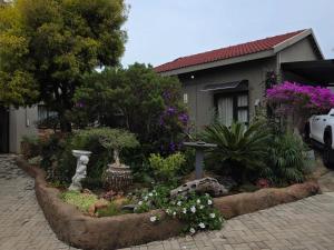 a garden in front of a house with flowers at Witteberg in Krugersdorp