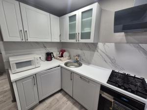 a white kitchen with a sink and a microwave at 2-room apartment with separate rooms in Narva
