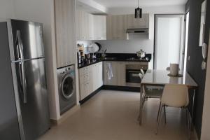 a kitchen with a stainless steel refrigerator and a table at Paradise évasion Bord de Mer avec Piscine in Pont Blondin