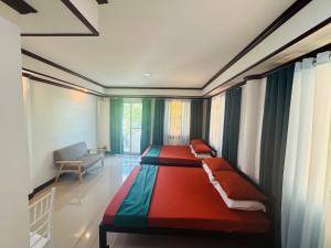 two twin beds in a room with a window at Tuburan Resort in Panong