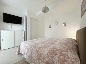 a white bedroom with a bed and a flat screen tv at Grazioso Bilocale della Rosa a Cadorago in Fino Mornasco