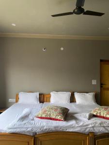 a bed with two pillows and a ceiling fan at Tsogstot residency in Deskit