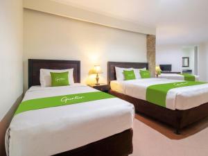 two beds in a room with green and white at Guntur Hotel Bali in Ketewel