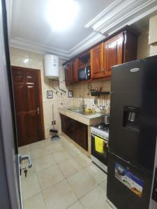 a kitchen with wooden cabinets and a black refrigerator at Studio VIP - 01 chambre - Bonamoussadi groupe électrogène - 2douches in Douala