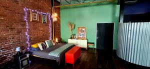 a bedroom with a bed and a brick wall at Cat-themed East City Loft Apartment in Cape Town