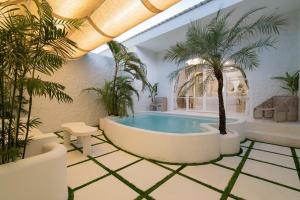 a swimming pool in a room with palm trees at Makyra by Bohemian Jogja Villas in Kejayan +7 photos
