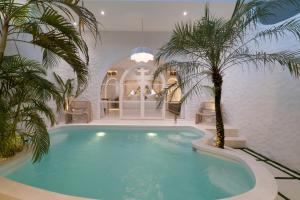 a swimming pool with a palm tree in a house at Makyra by Bohemian Jogja Villas in Kejayan