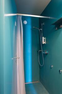 a blue bathroom with a shower with a shower curtain at Avenches Youth Hostel in Avenches +25 photos