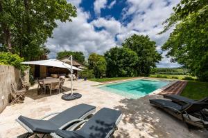 a swimming pool with lounge chairs and an umbrella at Le Loft - Château Le Noble in Saint-Germain-du-Puch