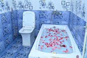 a bathroom with a toilet and a tub filled with flowers at Gitanjali Lodge in Rāmagiri Udayagiri