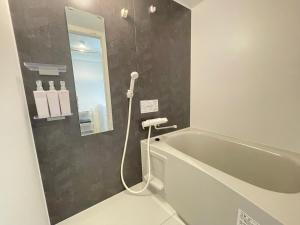 a bathroom with a bath tub and a mirror at エムズ千歳幸町2 in Chitose +13 photos