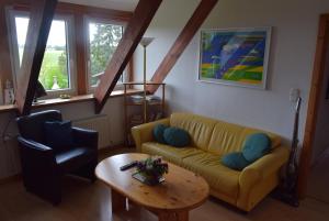 a living room with a yellow couch and a table at FeWo Vobbe in Dänischenhagen +4 photos