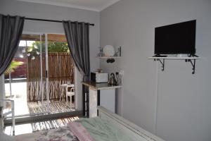 a living room with a tv and a bed and a balcony at Cozy Rustic Cottage in Windsor Park