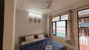 a bedroom with a blue bed and a window at Ghar by the mountains in McLeod Ganj