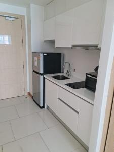 a kitchen with white cabinets and a black refrigerator at Beachfront A405 Seaview Studio Rawai Phuket in Ban Saiyuan (1)