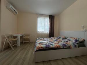 a bedroom with a bed and a table and a window at Равда Аполон 9 in Nesebar