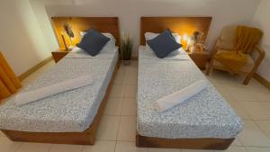 two beds in a room with pillows and a chair at Vozinha Residence in Prainha +15 photos