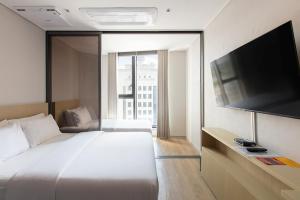 a bedroom with a large bed and a flat screen tv at HOMES Stay MyeongDong in Seoul