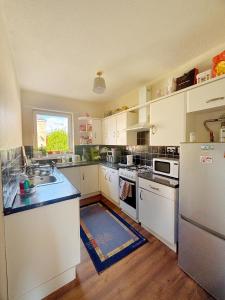 a large kitchen with white appliances and a window at Spacious room close to tram in Edinburgh