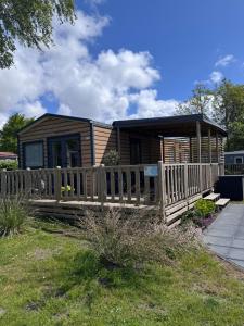 a wooden cabin with a porch and a fence at Chalet Pampusplaat 16 in Lauwersoog