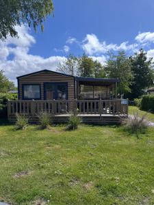 a log cabin with a large deck in a yard at Chalet Pampusplaat 16 in Lauwersoog
