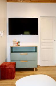 a tv on a wall with a blue dresser at Chalet l'Escale du Cèdre in Rivières